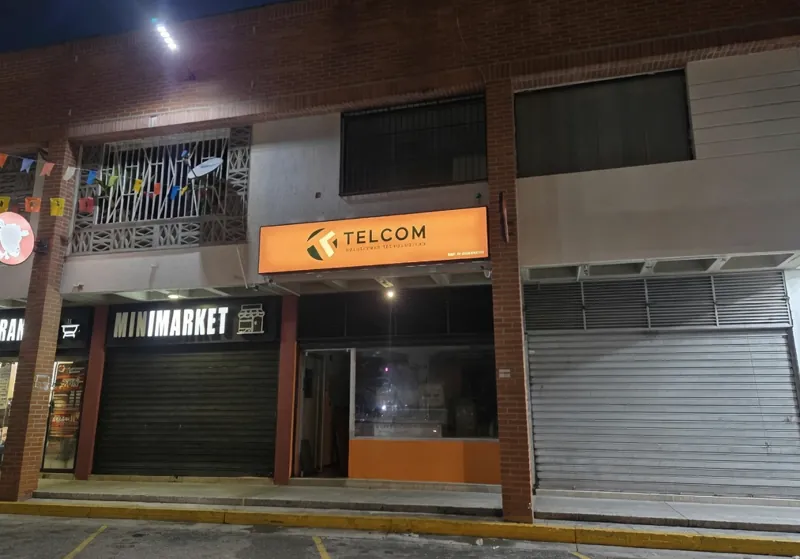 Fachada de la tienda Telcom en Mérida, con el letrero iluminado de noche